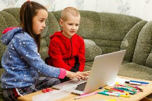 zwei schön süß glücklich lächelnd Kinder, ein Junge und ein Mädchen, verwenden Laptop zum Entfernung Lernen oder Unterhaltung. foto