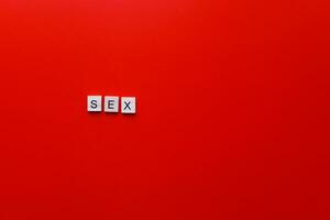 das Wort Sex von hölzern Briefe auf ein rot Hintergrund. foto