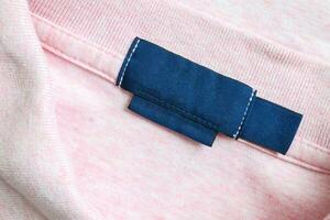 leer Blau Wäsche Pflege Kleider Etikette auf Rosa Hemd Stoff Textur Hintergrund foto