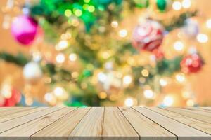 leere hölzerne tischplatte mit unscharfem weihnachtsbaum mit bokeh hellem hintergrund foto