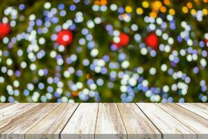 leere hölzerne tischplatte mit unscharfem weihnachtsbaum mit bokeh hellem hintergrund foto