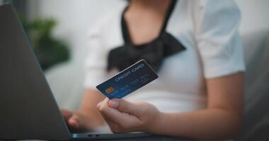 Porträt von jung asiatisch Frau Sitzung auf Sofa im Leben Zimmer, macht online Bankwesen Zahlungen durch das Internet von Bank Karte auf Laptop, Einkaufen online mit Anerkennung Karte. foto