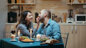 jung verheiratet Paar haben komisch Momente beim Abendessen. Ehefrau und Mann während romantisch Abendessen im das Küche, Essen zusammen beim heim, genießen das Mahlzeit, feiern ihr Jubiläum, Überraschung Urlaub foto