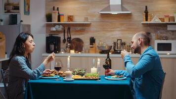 kaukasisch jung Paar haben romantisch Abendessen im das Küche nach Arbeit. glücklich Menschen reden, Sitzung beim Tabelle im Essen Zimmer, genießen das Mahlzeit, feiern ihr Jahrestag beim Zuhause mit gesund Essen foto