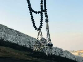 ein Halskette mit zwei schwarz Perlen und ein Silber Glocke hängend von ein Seil foto
