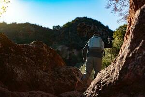 mittleren Alters Mann klettert das Berg im das garraf natürlich Park, unterstützt durch Wandern Stangen. foto