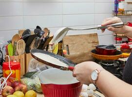 Hostess Kochen köstlich Pfannkuchen auf Gas Herd Bratpfanne beim Zuhause foto