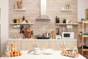 Gebäck Zutaten zum hausgemacht Kuchen und Brot im leeren Küche. modern Essen Zimmer ausgestattet mit Utensilien bereit zum Kochen mit Weizen Mehl im Glas Schüssel und frisch Eier auf Tabelle foto