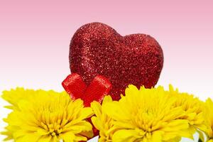 Strauß von Gelb Chrysanthemen mit rot glänzend Herz auf Rosa Hintergrund. Valentinstag Tag, Mutter Tag und International Damen Tag. Kopieren Raum foto