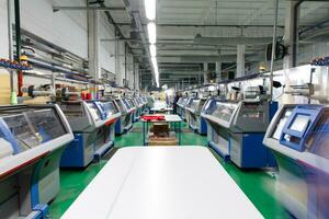 ein Reihe von industriell Textil eben Stricken Maschinen im ein Strickwaren Fabrik. foto