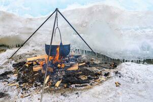 ein Feuer Topf mit zum Kochen Fisch Suppe während Camping auf See Baikal, Russland. lokal Fischer gekocht auf Feuer, mit das Hilfe von heiß Steine und Kohlen. foto
