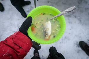 Tourist halten ein heiß von omul Fisch Suppe im Hand während Picknick im See Baikal, Russland. das omul Fisch ist ein endemisch Fisch zu See Baikalsee. foto