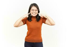 lächelnd und Finger berühren Wange von schön asiatisch Frau isoliert auf Weiß Hintergrund foto