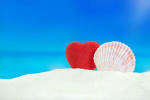rot Herz mit Muschel auf Sand von Strand hinter Meer. Valentinstag Tag, Hochzeit, Flitterwochen, Urlaub im heiß Länder. Kopieren Raum foto