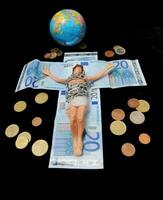 Jesus auf ein Kreuz mit Geld und ein Globus foto
