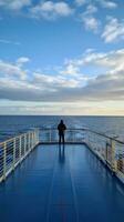 ai generiert ein heiter Bild von ein einsam Zahl Stehen auf das Deck von ein Kreuzfahrt Schiff foto