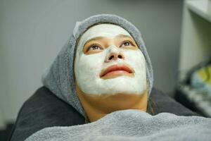 Nahansicht Schönheit Frau mit Weiß Maske Sahne auf ihr Gesicht im Schönheit Klinik. foto