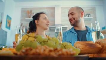 verlängert Familie Toasten mit Weiß Wein Brille während Abendessen, Wochenende Feier. multi Generation, vier Menschen, zwei glücklich Paare reden und Essen während ein Gourmet mael, genießen Zeit beim heim. foto