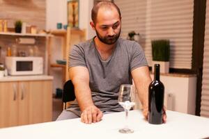 einsam Mann halten Flasche von rot Wein weil von Depression. unzufrieden Person Krankheit und Angst Gefühl erschöpft mit Schwindel Symptome haben Alkoholismus Probleme. foto