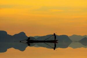 Silhouette von Fischer auf das See. foto