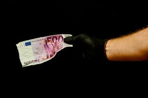 ein schwarz behandschuhte Hand halten ein Banknote foto