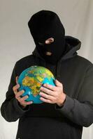 ein Mann im ein schwarz Kapuzenpullover halten ein Globus foto