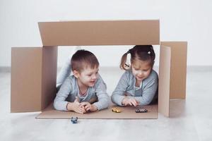 Babybruder und Kinderschwester spielen in Kartons im Kindergarten foto