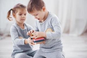 Kinder spielen mit einem Spielzeugdesigner auf dem Boden des Kinderzimmers. zwei Kinder spielen mit bunten Blöcken. Lernspiele im Kindergarten foto