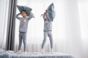 Kinder im weichen warmen Pyjama spielen im Bett