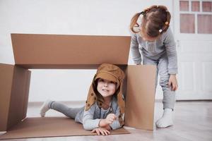 Babybruder und Kinderschwester spielen in Kartons im Kindergarten foto