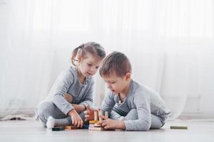 Kinder spielen mit einem Spielzeugdesigner auf dem Boden des Kinderzimmers. zwei Kinder spielen mit bunten Blöcken. Lernspiele im Kindergarten foto