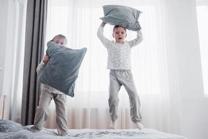 Kinder im weichen warmen Pyjama spielen im Bett