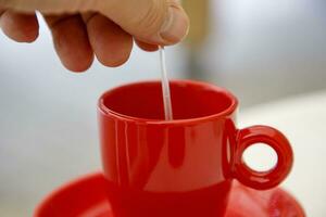 Hand Handbuch rühren im ein Tasse von Kaffee oder Tee. schließen foto