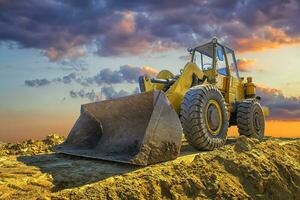 ein anhalten Gelb Bagger beim ein schön Sonnenuntergang foto