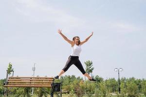 glückliche Frau, die im sonnigen Sommertag auf dem Sportplatz trainiert foto