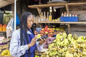 afrikanisch Markt Frau halten ein pos Gerät foto