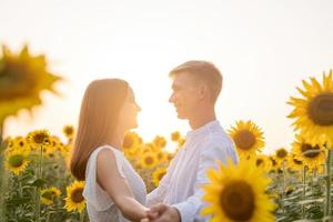 schönes Paar, das Spaß hat und in Sonnenblumenfeldern tanzt foto