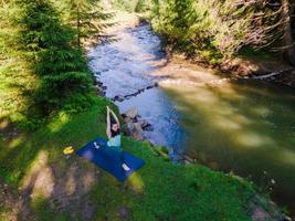 Frau macht Yoga am Flussstrand foto