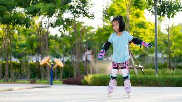 asiatisch Kind Mädchen üben Walze skaten. Kinder tragen Ellbogen bewachen und Knie bewachen zu verhindern stark Verletzungen verursacht durch Auswirkungen wann spielen herausfordernd Sport. Kind 6 Jahre alt. foto