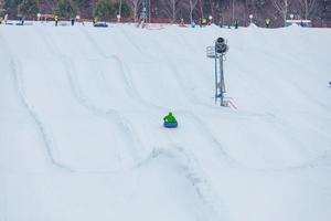 Leute, die im Winterpark Snowtubing fahren foto