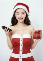 ai generiert Santa süß Mädchen halten ein Handy, Mobiltelefon Telefon und ein Geschenk auf ein Weiß Hintergrund ai generiert foto