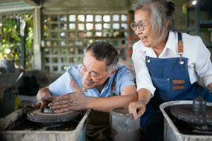 Porträt von ein Senior asiatisch Paar tun Aktivitäten zusammen im das Keramik Werkstatt. foto