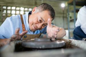 Porträt von ein Senior asiatisch Paar tun Aktivitäten zusammen im das Keramik Werkstatt. foto