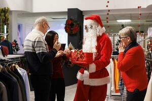 Menschen finden aus Wettbewerb Gewinner im Geschäft nach Mann gekleidet wie Santa Zeichnung Preis- Namen von rot Kasten, Herstellung jemand glücklich mit kostenlos Kleidung Artikel während Weihnachten. Kunden warten ungeduldig. foto