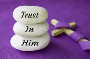 Vertrauen im ihm Text auf Steine mit Christian Kreuz Hintergrund. Gebet und Christentum Konzept foto