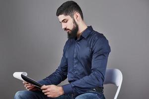 konzentrierter junger attraktiver Geschäftsmann in blauem Hemd, der in der Zwischenablage plant und schreibt