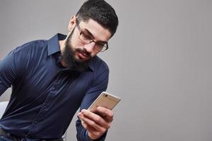 glücklicher Mann mit Brille, der SMS auf grauem Hintergrund schreibt