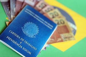 Brasilianer Arbeit Karte und Sozial Sicherheit Blau Buch und reais Geld Rechnungen auf Flagge von föderativ Republik von Brasilien foto