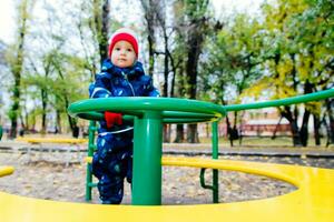 das Kind ist Spinnen auf ein schwingen im das Spielplatz im das Park foto