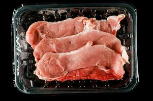 drei roh Schweinefleisch Koteletts im ein Plastik Container foto